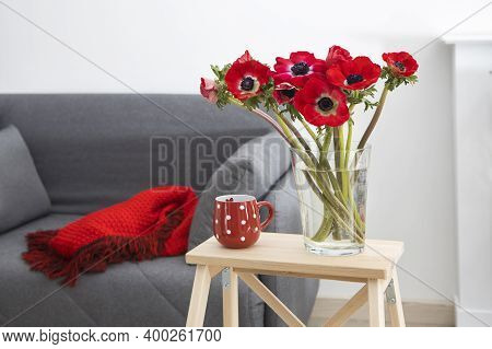 A Bouquet Of Red Anemones In A Transparent Glass Vase On A Table With A Gray Tablecloth. White Polka