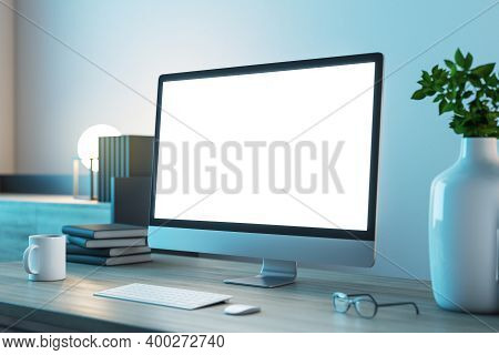 Blank White Computer Monitor Screen On Table With Office Supplies. Workplace And Technology Concept.