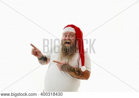 Portrait On A White Background Of An Overweigh Man In Santa Claus Hat Gesturing With Finger. Copy Sp