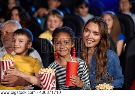 Mother Enjoying Time With Half African Little Daughter, Kid Sitting On Knees, Holding Drink And Popc