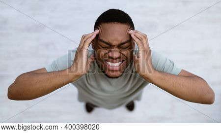 Top View Of Black Man Having Headache Suffering From Migraine Pain, Touching Aching Head Standing In