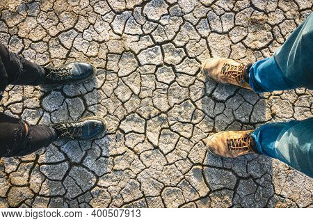 Two Person Feet On Beautiful Texture Dry Mud Volcanoe Ground With Blank Space In Middle