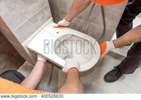 Workers Are Installing A Wall-hung Toilet On The Wall.