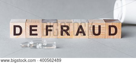 Defraud Is A Word Written In Black Letters On Wooden Cubes