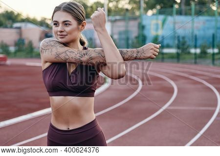 Beautiful Sporty Girl In Sportswear Dreamily Doing Hand Stretching Exercise While Tranining On City 