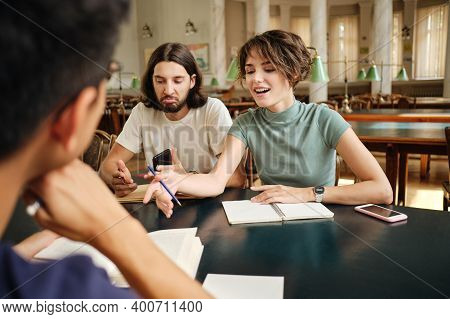 Young Attarctive Casual Students Emotionally Discussing Project Together In Library Of University