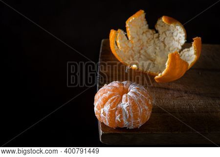 Peeled Tangerine On A Wooden Surface. Citrus Fruit. A Peeled Tangerine Lies Next To A Tangerine Peel