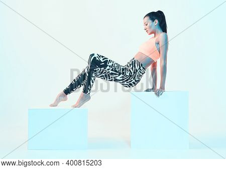 Sporty Fit Girl In Stylish Sportswear Sitting On Cube In Neon Studio Light. Perfect Body Shapes. Hea