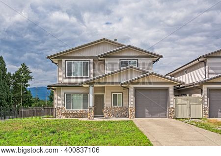 Half Of Residential Duplex Building With Concrete Driveway And Lawn In Front