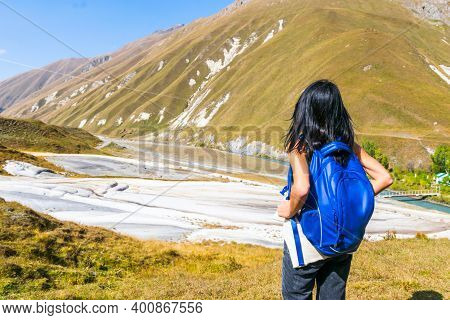 Female Black Hair Woman With Backpack Stands And Looks To White Treventines In Truso Valley. Georgia