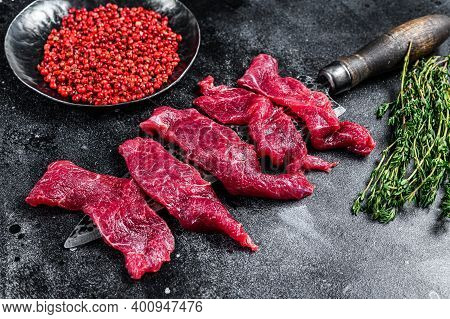 Raw Marbled Meat Cut Into Thin Strips For Beefstroganoff. Black Background. Top View