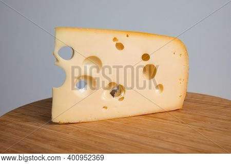 Yellow Cow's Milk Swiss Cheese Emmenthal With Holes On Wooden Board.