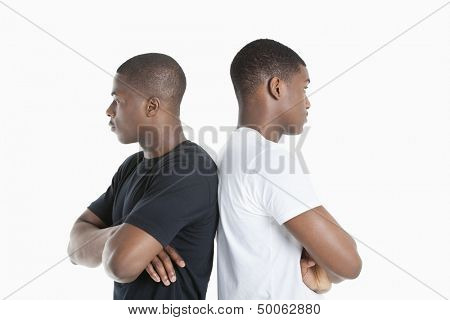 Two male friends standing back to back over gray background