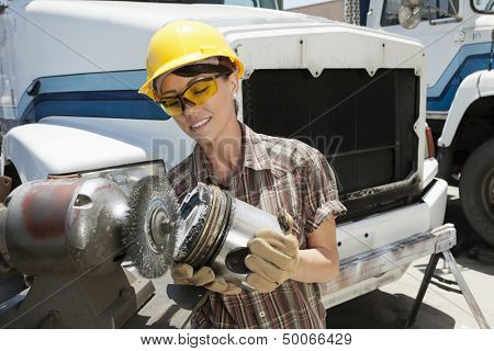 Female industrial worker buffing a truck engine cylinder