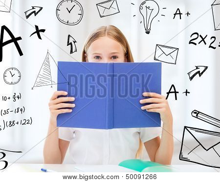 education and school concept - little student girl studying and reading book at school