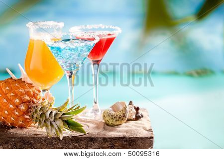 Glasses of cocktails on table near seea on beach