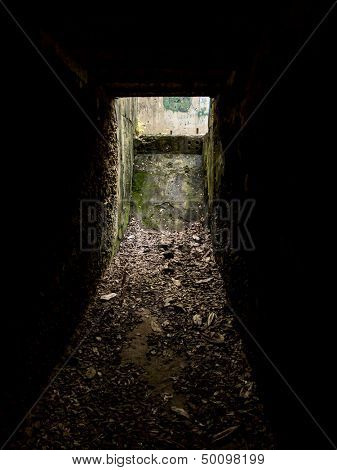 underground corridor full of debris with light at end
