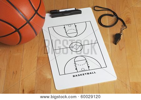 A Basketball With Coach's Clipboard And Whistle On A Wooden Gymnasium Floor