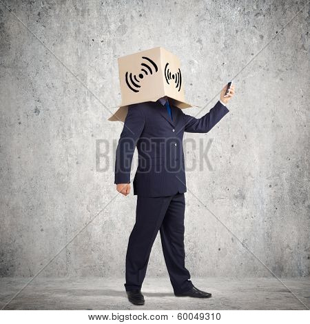 Businessman using mobile phone wearing carton box on head