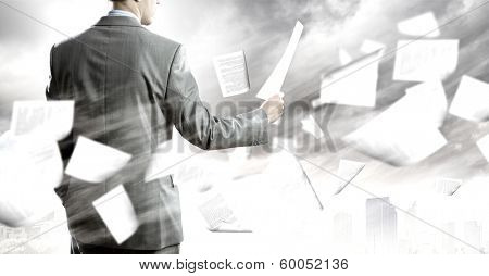 Back view of businessman reading documents in hand