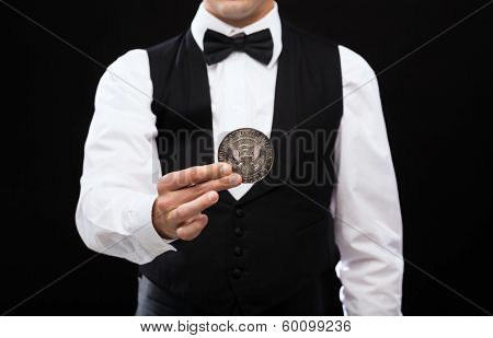 magic, performance, circus, casino and show concept - casino dealer holding half dollar coin