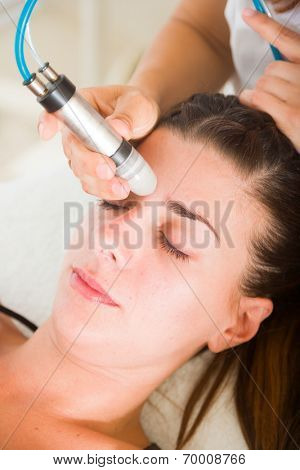 woman having a stimulating facial treatment from a therapist