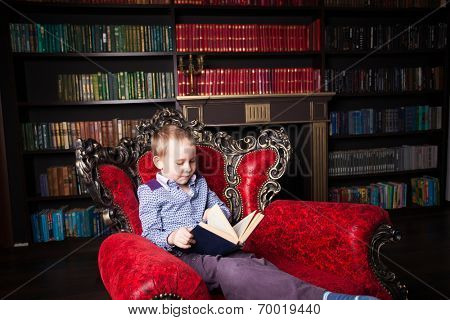 Boy reading book at home. Child in library