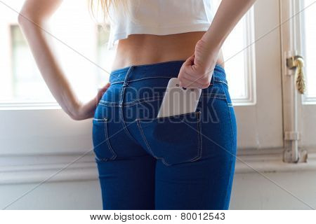 Young Beautiful Woman At Home With Mobile Phone In Back Pocket.