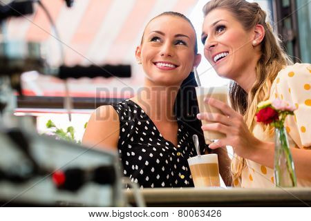 Two girls, best friends, drinking latte macchiato in cafe or coffee bar