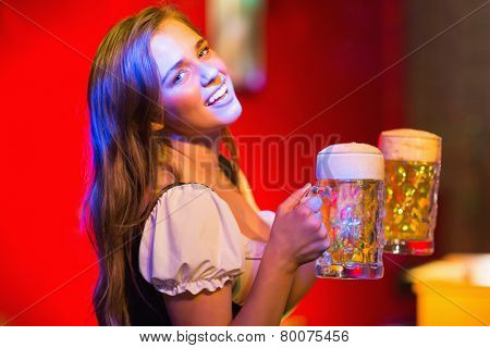 Smiling oktoberfest barmaid with beer at the bar