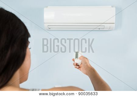 Woman Operating Air Conditioner With Remote Control