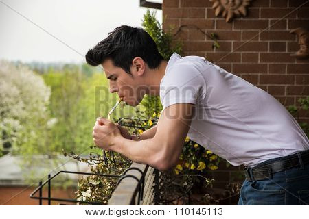 Handsome young man smoking a cigarette outside