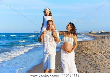 Happy family on the beach sand walking with pregnant mother woman