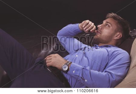 Young man in blue shirt relaxing on a sofa