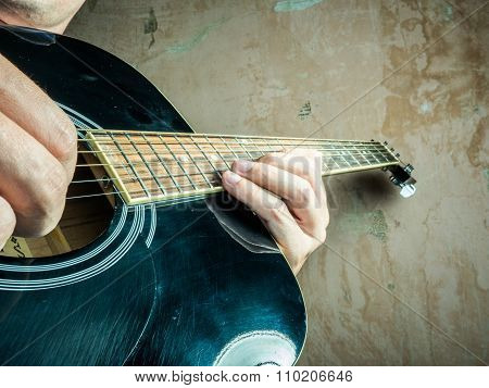Closeup photo of an acoustic guitar played by a man.