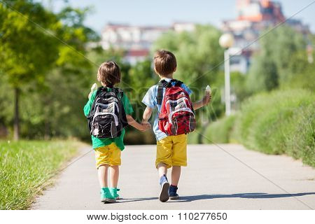 Two Adorable Boys In Colorful Clothes And Backpacks, Walking Away, Holding And Eating Ice Cream