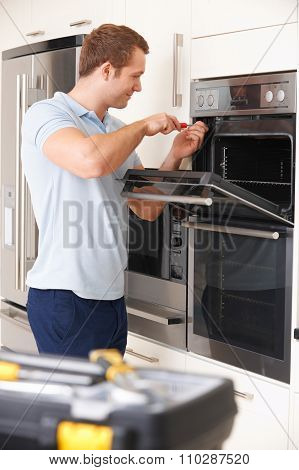 Engineer Reapiring Domestic Oven In Kitchen