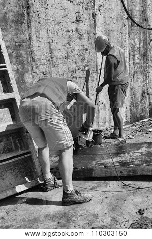 Compilation of metal structures for pouring concrete. Preparations for the inundation of supporting walls. The metal frame and the reinforcing mesh. Working fasten metal plate on a construction site.