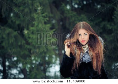 beautiful smiling girl on background of snowy trees. Winter portrait. coat with a hood