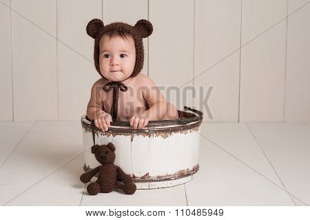 Baby Girl Wearing A Bear Bonnet With Matching Bear Toy