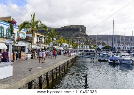 PUERTO DE MOGAN - NOVEMBER 27: Tourists enjoy the sunny weather and walking along the quay at the marina on 27 November 2015 in Puerto de Mogan, Gran Canaria Island.