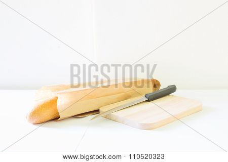 Baguette and paper container on wooden table