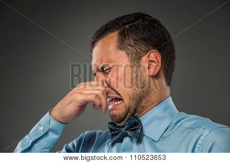 Young man - disgusted expression closing his nostrils with finge