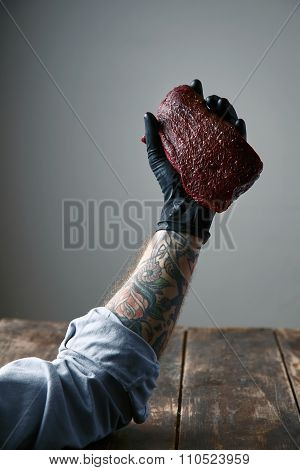 Tattooed Left Hand Black Silicon Glove Holds Fresh Whale Meat Steak