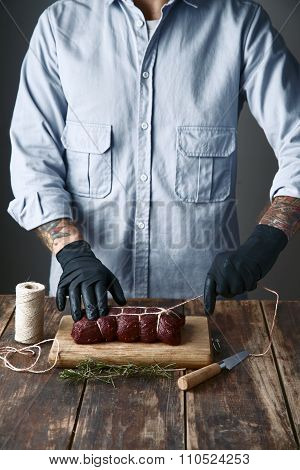 Butcher Ties Meat With Rope To Smoke , On Table With Species