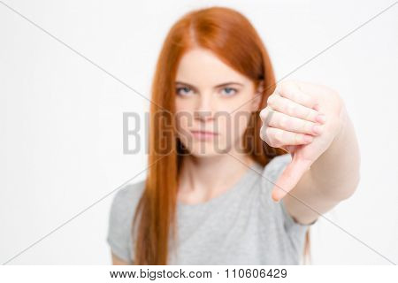 Angry frustrated young redhear female showing thumbs down  over white background