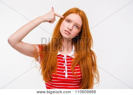 Depressed sad redhead young woman with long beautiful hair and a finger to her temple like a gun