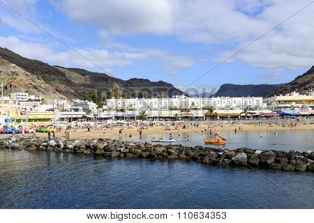 PUERTO DE MOGAN - NOVEMBER 27: Tourists enjoy the sunny weather and relaxing on the Atlantic ocean beach on 27 November 2015 in Puerto de Mogan, Gran Canaria Island.