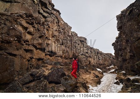 Man exploring lava rock formations in tectonic plate crack crevice in thingvellir national park iceland
