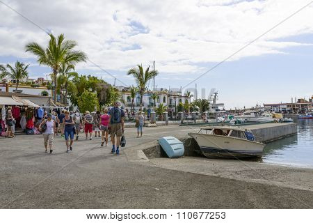 PUERTO DE MOGAN - NOVEMBER 27: Tourists enjoy the sunny weather and walking along the quay at the marina on 27 November 2015 in Puerto de Mogan, Gran Canaria Island.